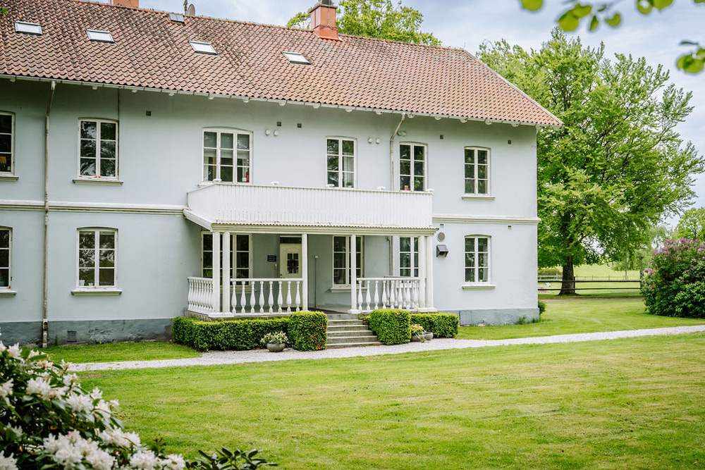 Ett vackert ljusblått hus med en stor grön gräsmatta runtom.