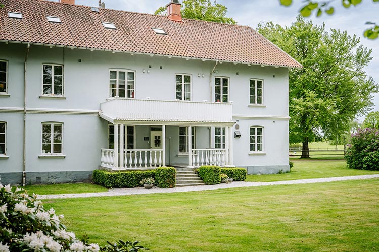 Ett vackert ljusblått hus med en stor grön gräsmatta runtom.